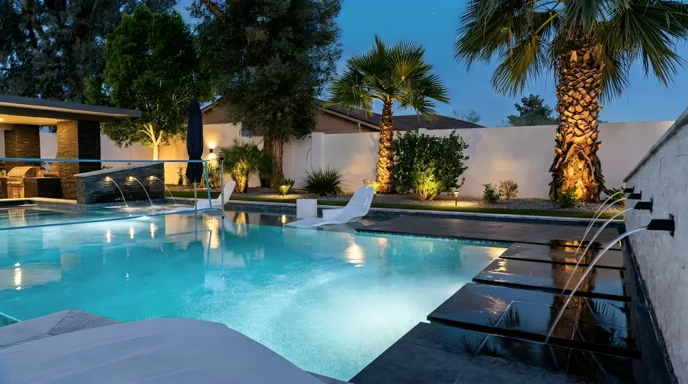 Luxury Arizona backyard pool illuminated at night with fire and water features
